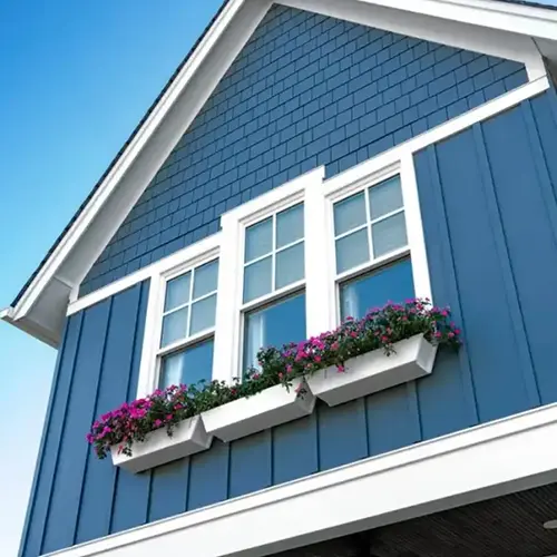 A beautifully finished home exterior with blue siding, white-framed windows, and flower boxes. Elevate your home’s curb appeal with expert exterior services from Dagmar Pros LLC