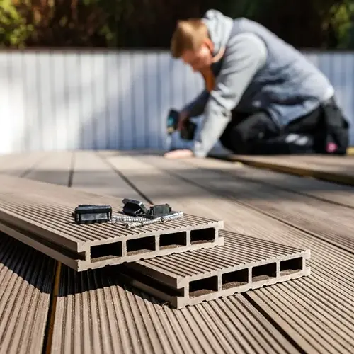  worker installing composite decking with tools and materials in the foreground. Create the perfect outdoor space with high-quality deck installation from Dagmar Pros LLC