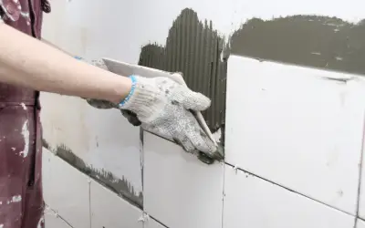 person in the midst of diy bathroom remodel doing hard work of laying tiles