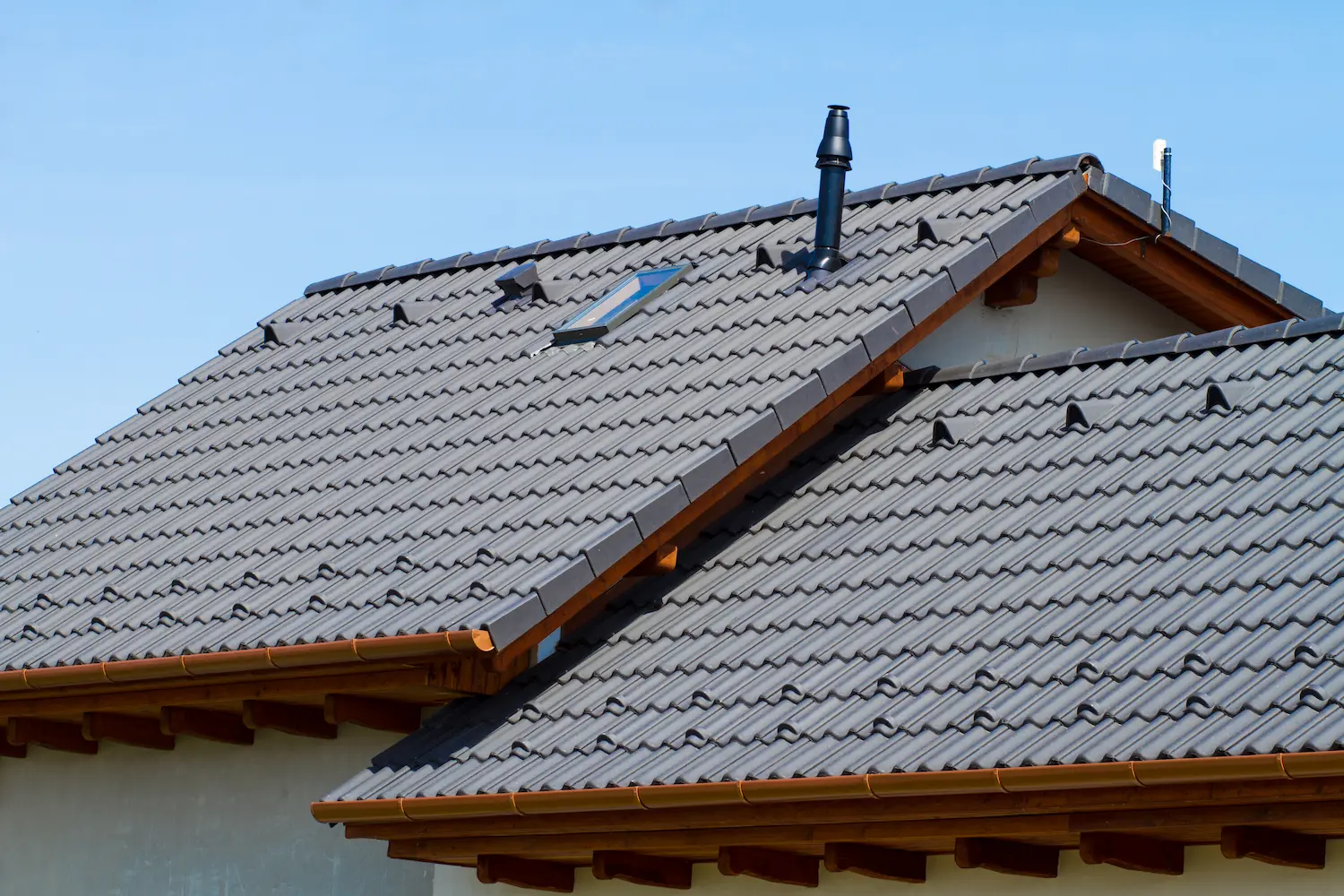 Modern roof of a detached house with gray concrete shingles against the blue sky in the Pacific Northwest